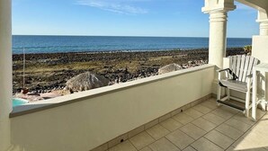 Un balcon avec vue sur l’océan et une plage rocheuse.