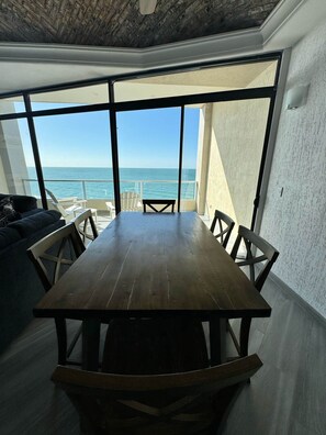 Ein Essbereich mit einem Holztisch und Stühlen, große Fenster mit Meerblick.