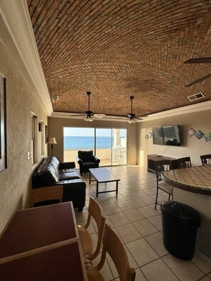A spacious living area with a high ceiling, a large TV, and a view of the sea. - Palacio Del Mar 206 - Rocky Point Oceanfront Vacation Rental (Puerto Peñasco)