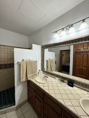 Une salle de bain avec un grand miroir, deux lavabos, des meubles en bois et un porte-serviettes.
