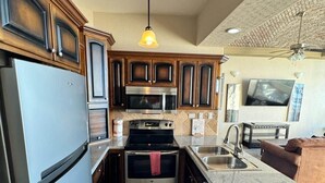 Cocina compacta con refrigerador, estufa, microondas y pileta.