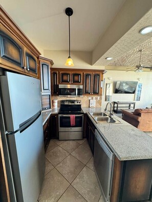 A compact kitchen with a refrigerator, stove, microwave, and sink. - Palacio Del Mar 404 - Rocky Point Oceanfront Vacation Rental (Puerto Peñasco)