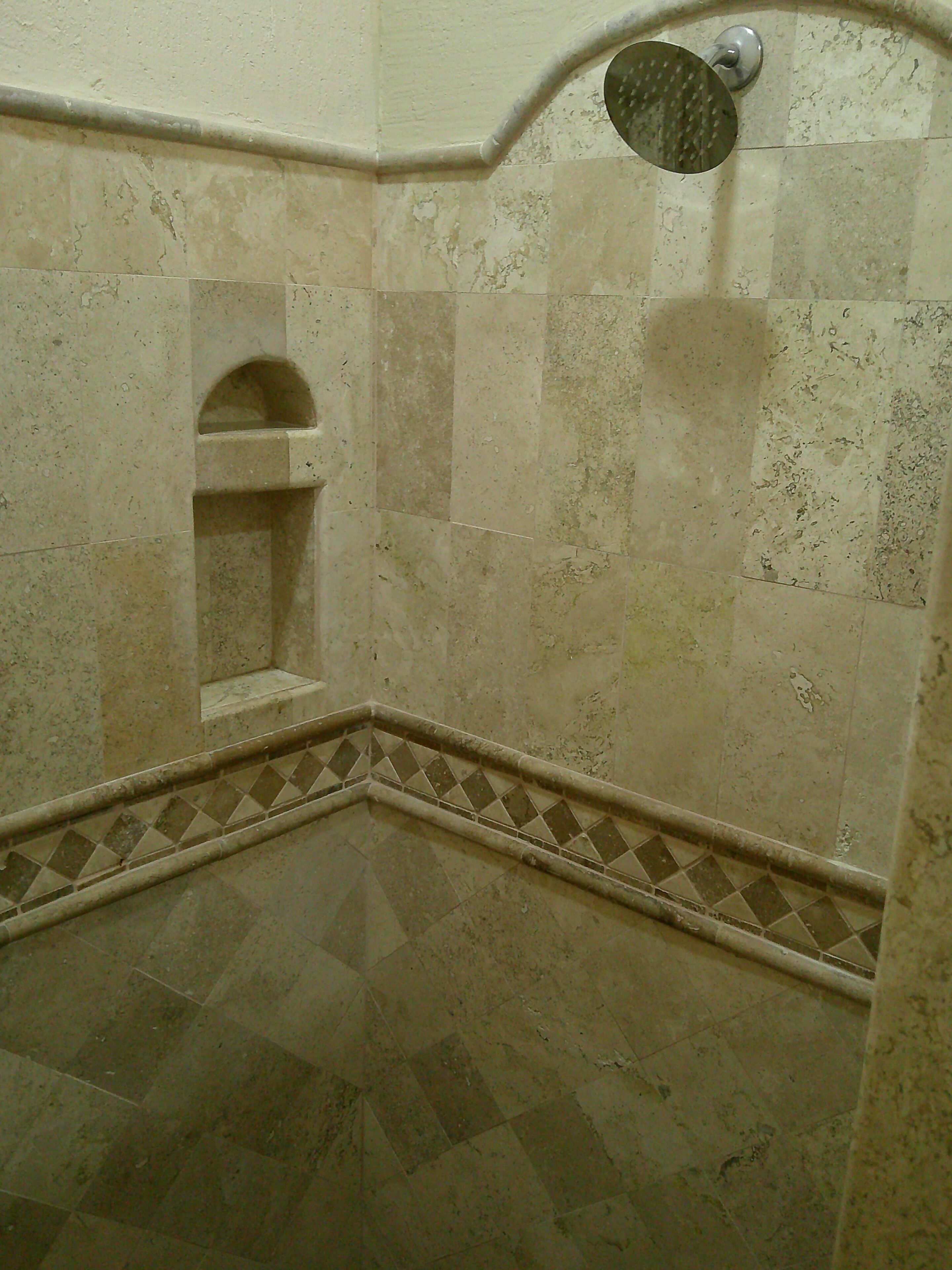 Une salle de bain avec un sol carrelé, un espace douche et une petite alcôve dotée d’un mur incurvé.
