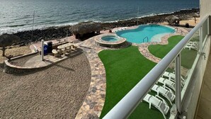 A pool area with a view of the ocean, a thatched-roof structure, and a stone pathway. - Palacio Del Mar 202 - Rocky Point Oceanfront Vacation Rental (Puerto Peñasco)