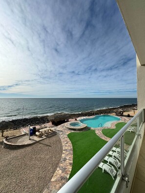 A pool area with a view of the ocean, a thatched-roof structure, and a stone pathway. - Palacio Del Mar 202 - Rocky Point Oceanfront Vacation Rental (Puerto Peñasco)