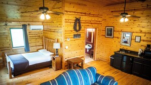 A log cabin-style room with a bed, a sofa, a kitchenette, and a bathroom. - Horseshoe Canyon Ranch (Jasper)