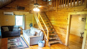 A wooden cabin interior with a staircase, a sofa, a fan, and a ceiling fan. - Horseshoe Canyon Ranch (Jasper)