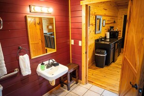 A compact bathroom with a sink, mirror, and towel rack.