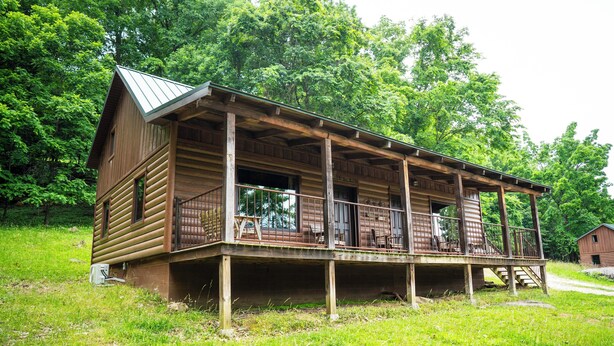 A wooden cabin with a porch, surrounded by lush greenery. - Horseshoe Canyon Ranch (Jasper)