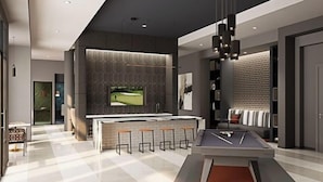 A modern kitchen with a bar area, a pool table, and a large TV screen. - Landing Furnished Apartments West Huntsville (Huntsville)