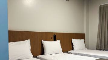 Habitación de hotel con dos camas, cabecera de madera, aire acondicionado montado en la pared y una ventana con cortinas.