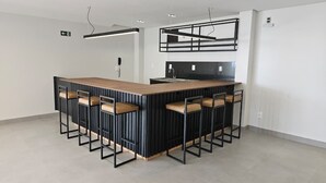 Una cocina moderna con una isla central, taburetes negros tipo barra e iluminación colgante.