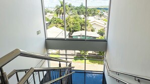 Una escalera con barandillas de metal que conduce a un balcón con vista a una zona residencial.