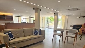 Amplia sala de estar con sofá, dos sillas de madera y una mesa de madera.