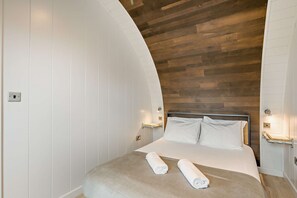 A bedroom with a curved white wall, a wooden ceiling, a bed with white linens, and two bedside lamps. - Host & Stay | Secret Garden (Beccles)