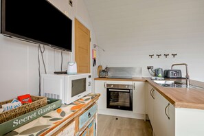 A compact kitchen with a microwave, oven, and a small sink. - Host & Stay | Secret Garden (Beccles)