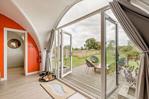 A room with a large glass door leading to an outdoor deck with chairs and a table.