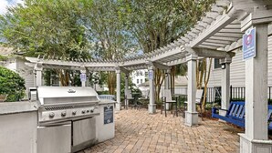 Um pátio externo com churrasqueira, área de estar e pérgola.