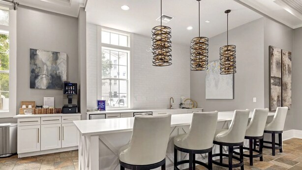 Cozinha moderna com ilha central, banquetas, luminárias pendentes e uma janela grande.