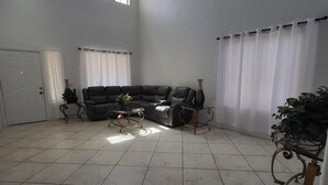 A spacious living room with a large sectional sofa, a coffee table, and a potted plant. - La Rosa Phoenix (Phoenix)