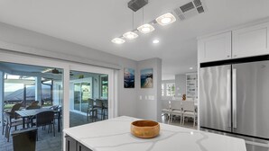 Cocina moderna con una isla grande, electrodomésticos de acero inoxidable y un área de comedor con asientos al aire libre.