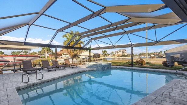 Una piscina con una estructura metálica de techo geométrico, rodeada de sillones de descanso y un pequeño elemento acuático.