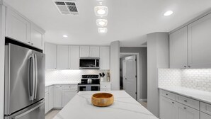 Una cocina moderna con armarios blancos, electrodomésticos de acero inoxidable y encimera de mármol.