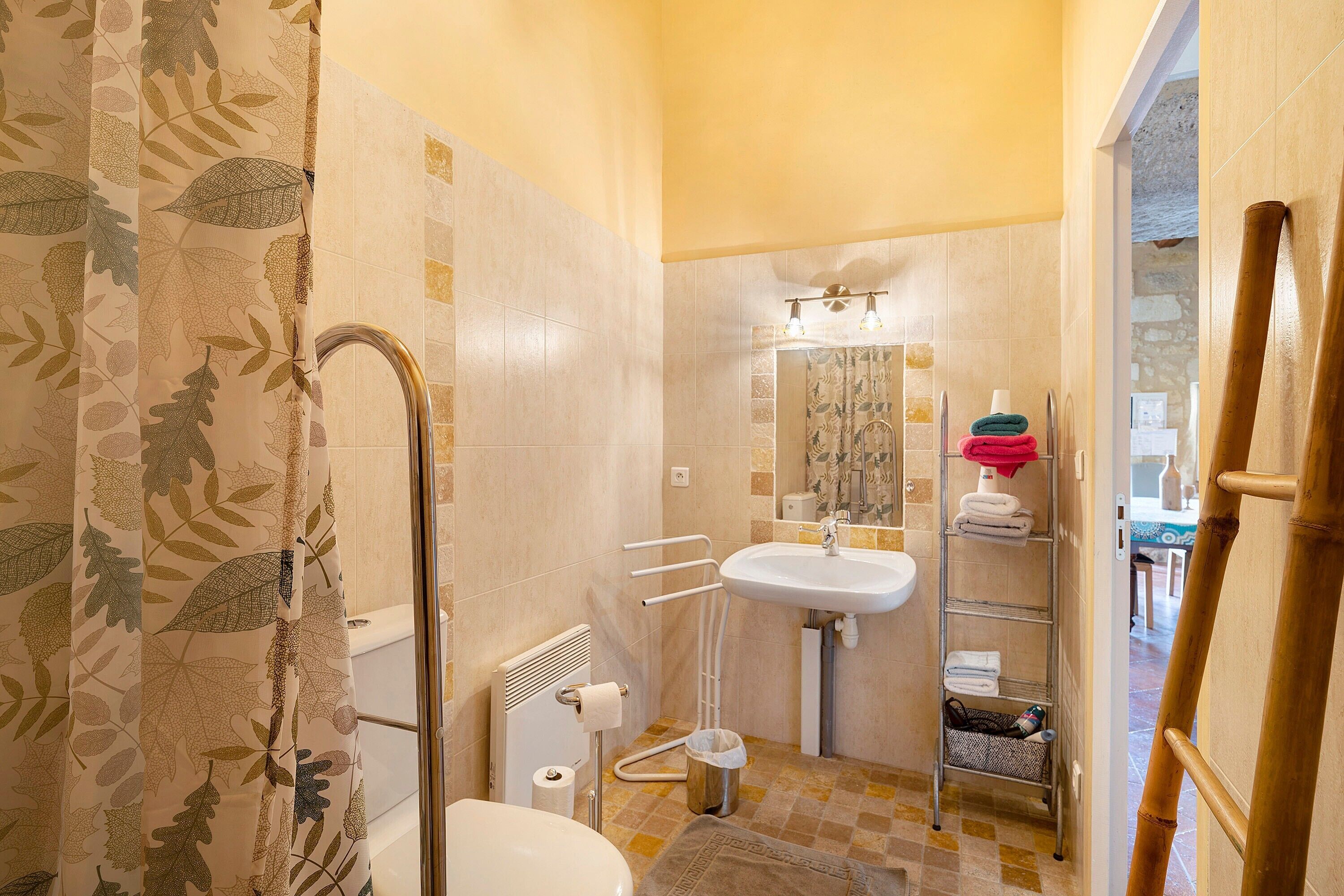 Une salle de bain équipée d’un rideau de douche, de toilettes, d’un lavabo et d’un porte-serviettes.