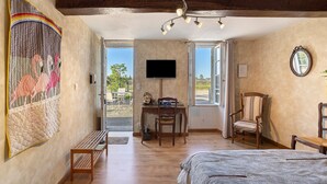 Un dormitorio con cama, escritorio, silla, televisor y un ventanal grande.