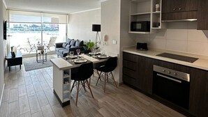 Une cuisine moderne avec un coin repas, un plancher en bois et une vue dégagée grâce à de grandes fenêtres.