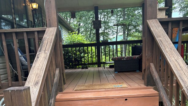 A wooden staircase leading up to a covered porch with a view of greenery.