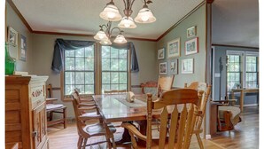 A dining area with a wooden table and chairs, a chandelier, and framed pictures on the walls.