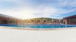 A swimming pool with lounge chairs and umbrellas, surrounded by buildings with a clear view of a forested hill in the background. - Relaxing 1-bedroom resort with AC in peaceful Preah Sihanouk #4 (Preah Sihanouk,)