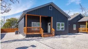 A two-story building with a porch, a wooden staircase, and a gravel driveway. - Bright and Fancy 3-Bedroom Near Fun Riverwalk! (San Antonio)
