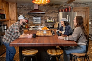 A kitchen with a brick wall, wooden cabinets, a stainless steel refrigerator, and a sign that reads "HOME sweet HOME". - Renovated Tahoe House: Hot Tub, Fire Pit, Pool Table, Fenced Yard for Kids+Pets (South Lake Tahoe)