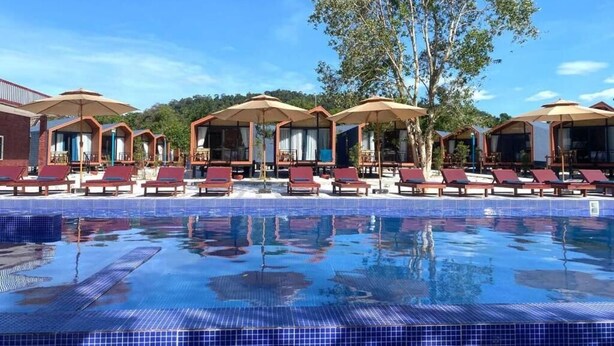 A pool area with lounge chairs and umbrellas, surrounded by a tiled pool. - Relaxing 1-bedroom resort with AC in peaceful Preah Sihanouk #6 (Preah Sihanouk,)