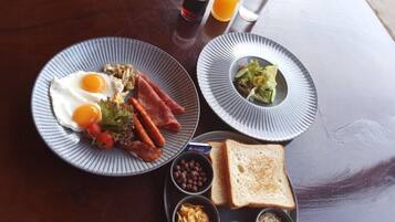 Un plateau de petit-déjeuner avec des œufs, du bacon, des toasts, des haricots et une salade.