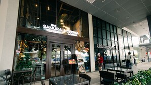 Un restaurant dont l’entrée est décorée sur le thème des samouraïs, et où l’on aperçoit de l’autre côté de la rue un restaurant spécialisé dans les poulets et les hamburgers.