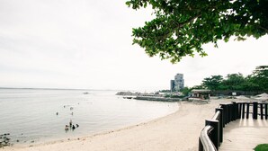 Une plage avec une promenade en bois, une eau calme et un bâtiment situé au loin.
