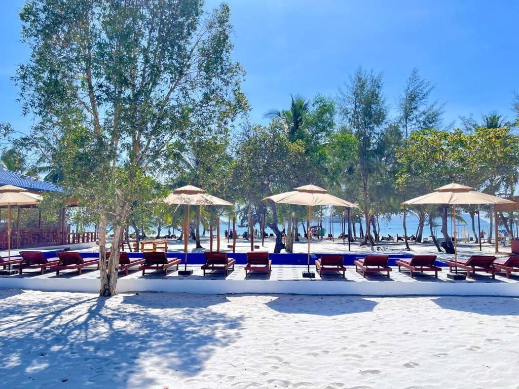 A beachside lounge area with sun loungers and umbrellas, surrounded by trees and a clear view of the ocean. - Relaxing 1-bedroom resort with AC in peaceful Preah Sihanouk #8 (Preah Sihanouk,)