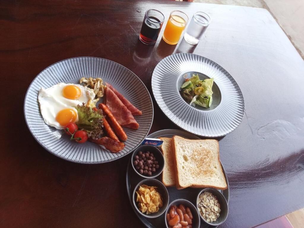 Un plateau de petit-déjeuner avec des œufs, du bacon, des toasts, des haricots et une salade.