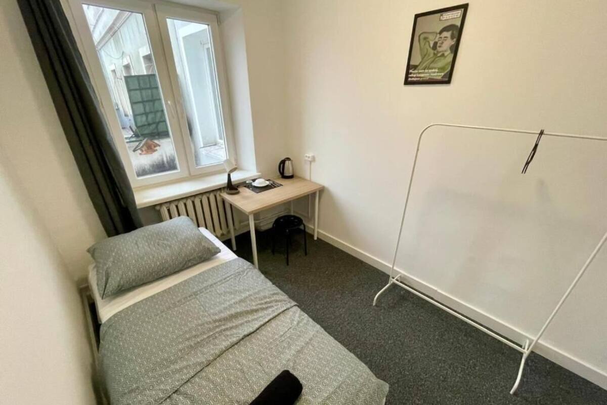 A small, simple room with a bed, a desk, and a radiator.