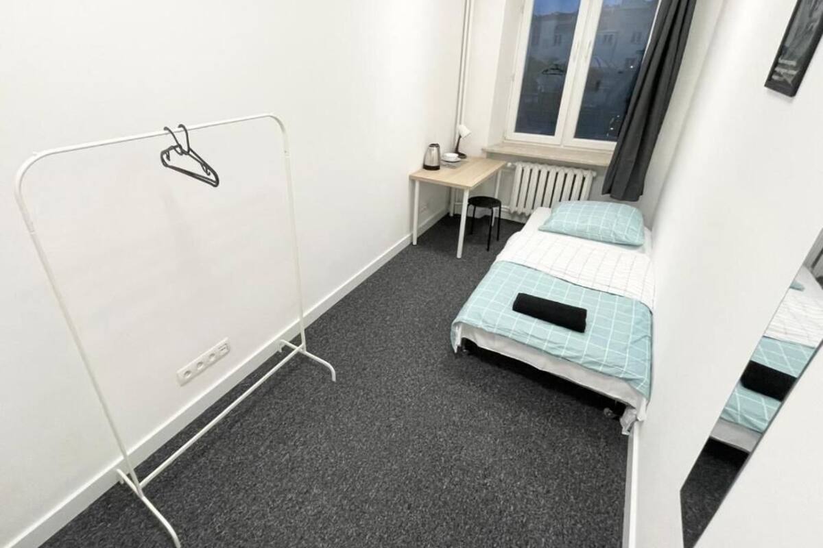 A small, compact room with a single bed, a desk, and a radiator.