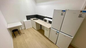 Una cocina compacta con microondas, refrigerador y lavamanos.