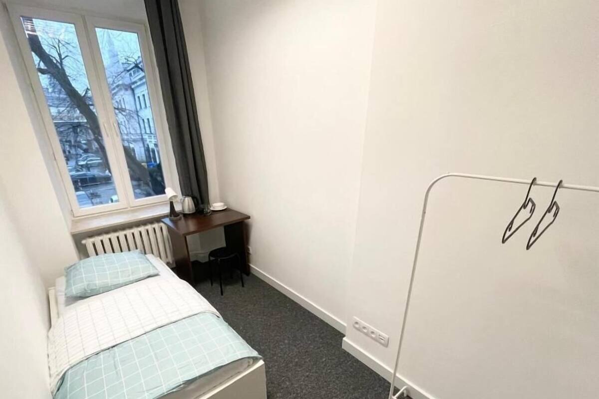 A small hotel room with a bed, a desk, and a radiator.