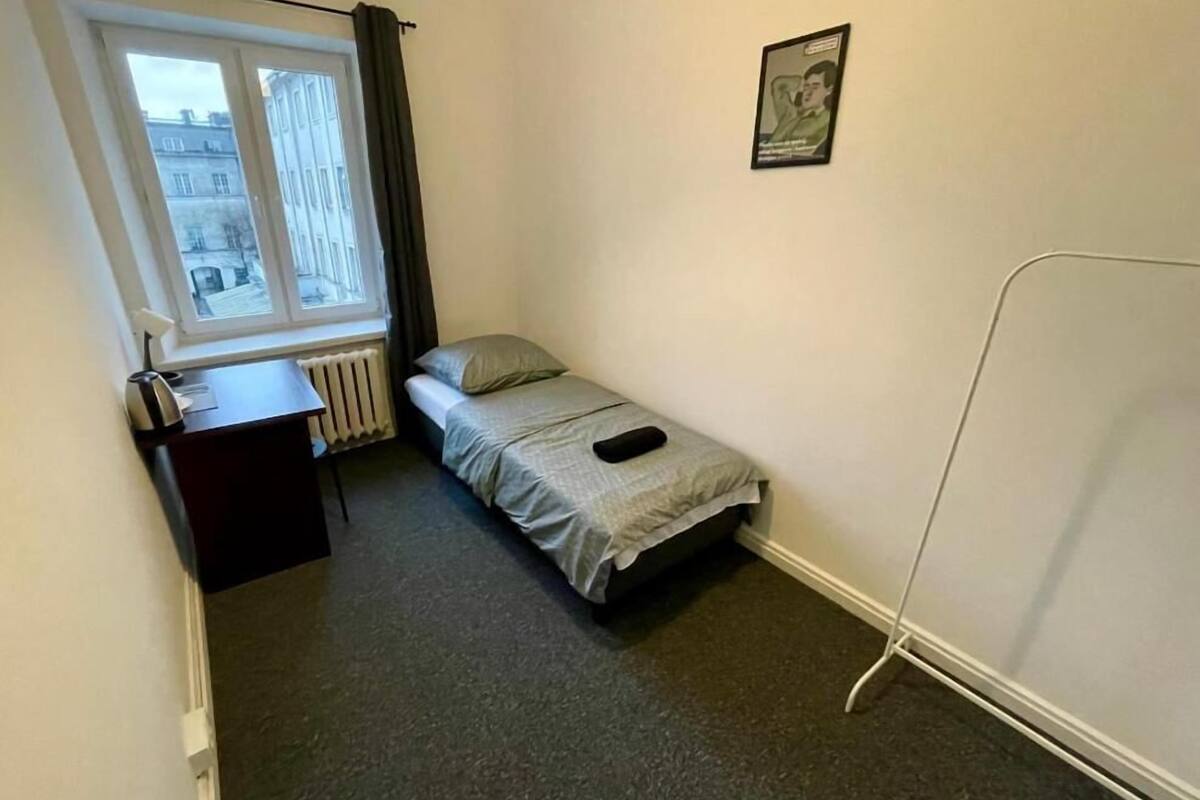 A small, compact room with a single bed, a desk, and a radiator.