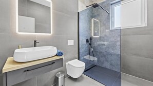 Un bagno moderno con un ampio lavandino bianco, un water e una cabina doccia in vetro.