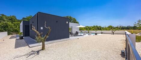 Ein modernes Gebäude mit Kiesterrasse, Sitzmöglichkeiten im Freien und einem Pool.