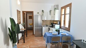 Une cuisine compacte avec un coin repas, comprenant un réfrigérateur, une cuisinière, un four à micro-ondes et une table dressée pour deux personnes.