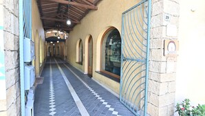 Un couloir doté d’un sol carrelé, de fenêtres en arc de cercle et d’une grille métallique.